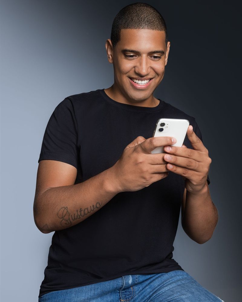 Homem sorrindo enquanto usa o celular
